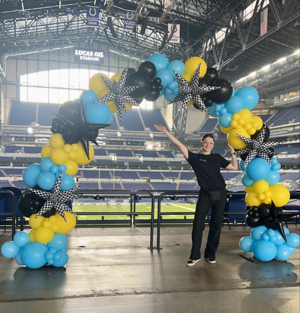 Alexis proudly displays her yellow, black, and blue balloon arch at Lucas Oil Stadium.