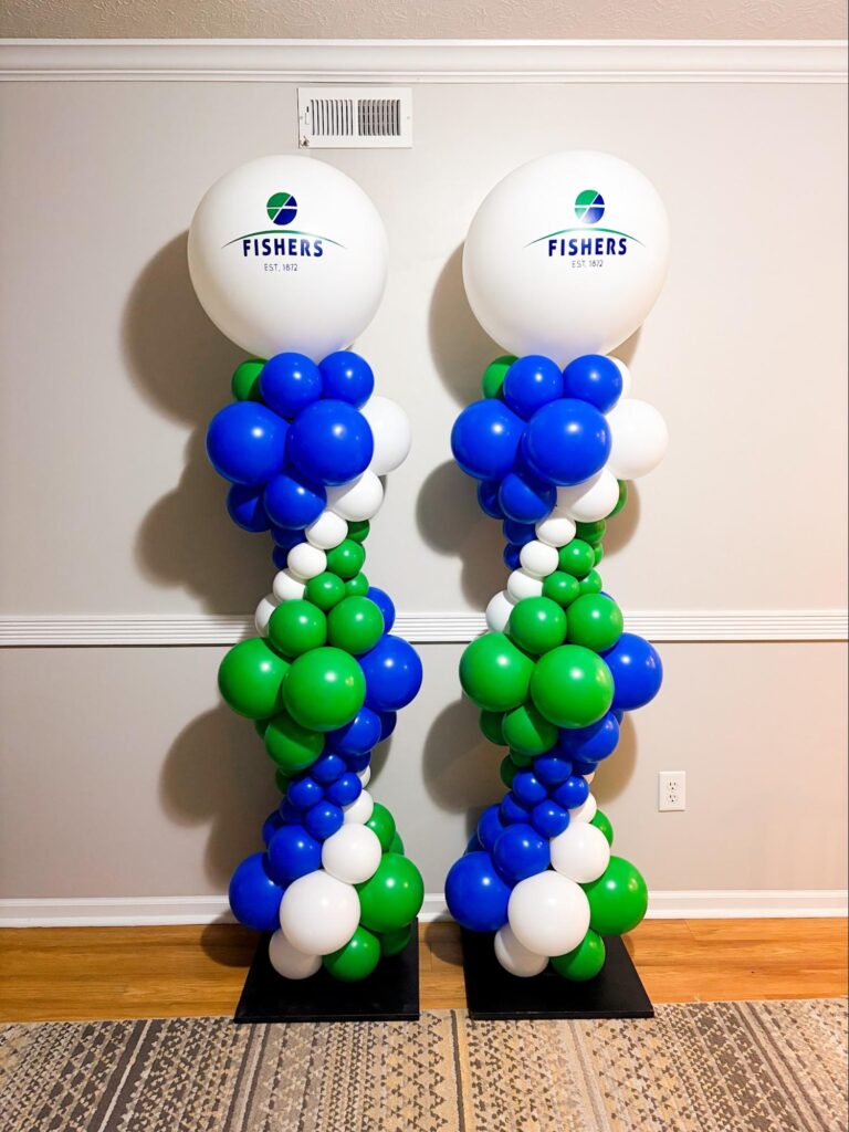 Two balloon columns of blue, green, and white balloons with giant white balloons on top that say "City of Fishers".