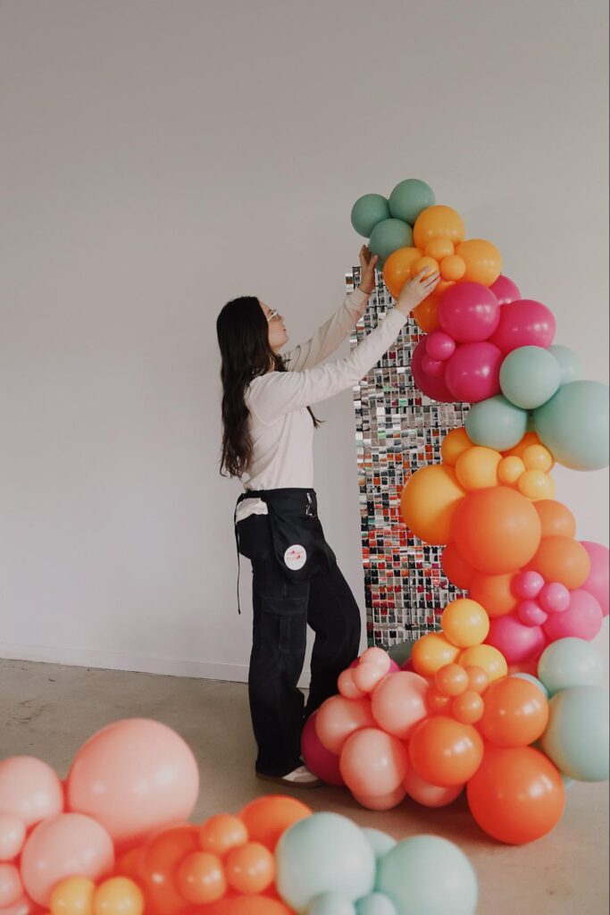 Alexis adjusts the orange balloons in her large balloon design.